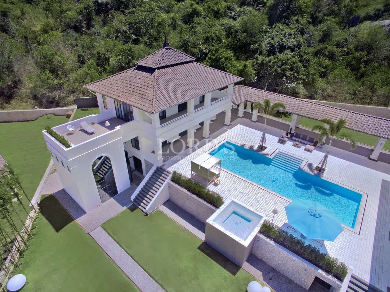 Aerial view of a luxury hillside villa with private swimming pool, terrace lounge area, and landscaped garden.
