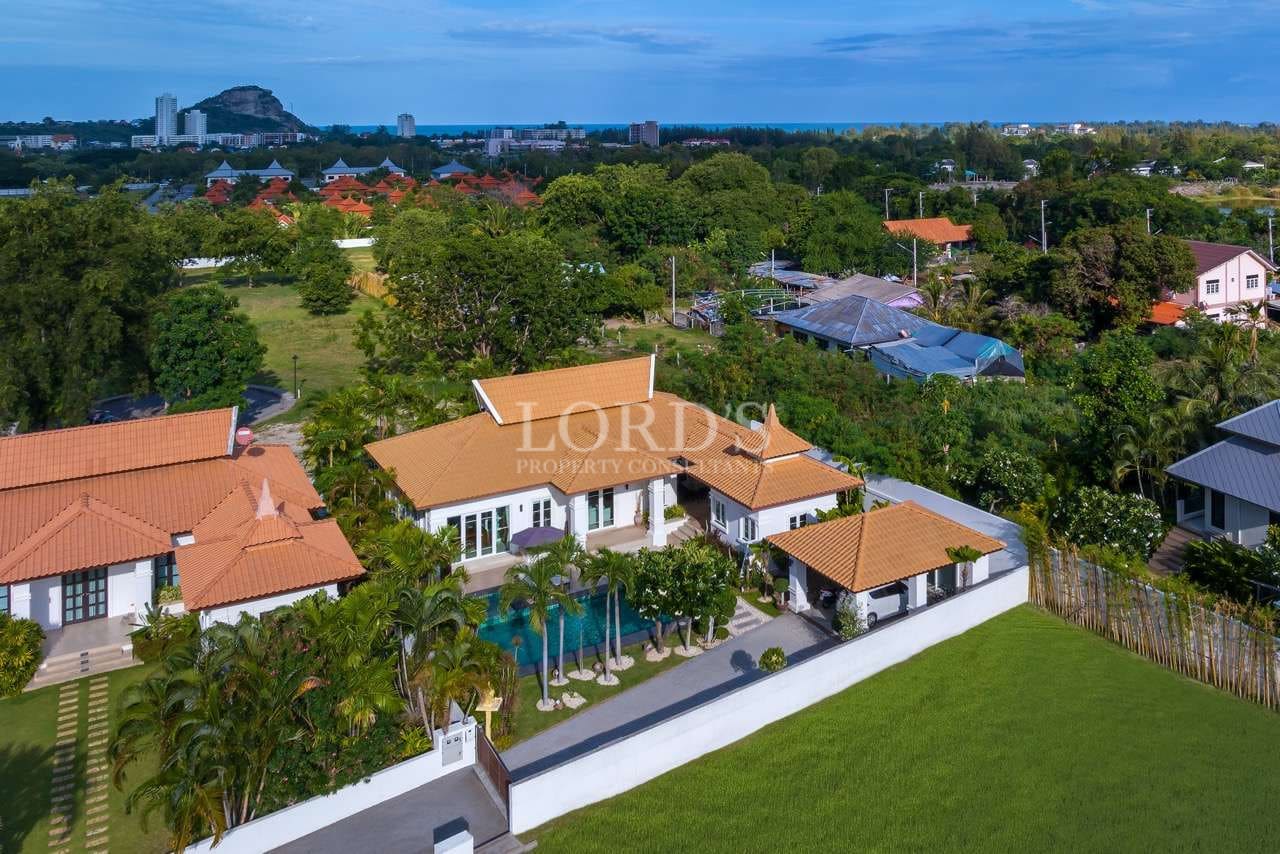 Aerial view of a luxury tropical villa with private swimming pool, garden, and surrounding greenery.