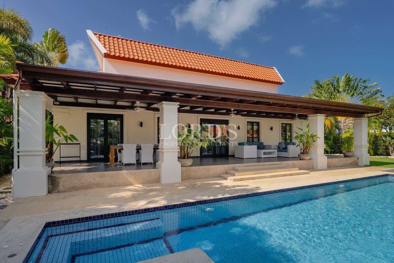 Luxury poolside villa with covered terrace, outdoor seating, and modern tropical architecture.