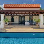Luxury villa with covered terrace and swimming pool, featuring tropical landscaping and modern outdoor seating.