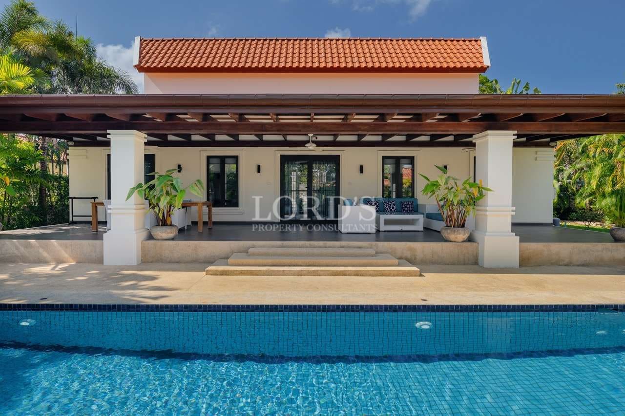 Luxury villa with covered terrace and swimming pool, featuring tropical landscaping and modern outdoor seating.