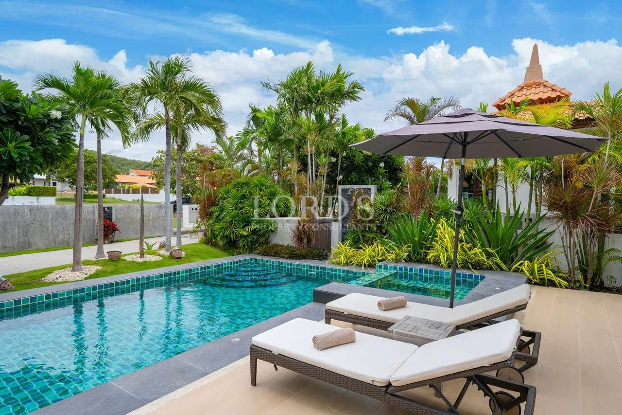 Luxury private pool with sun loungers, umbrella, tropical palm trees, and landscaped garden in a modern villa.