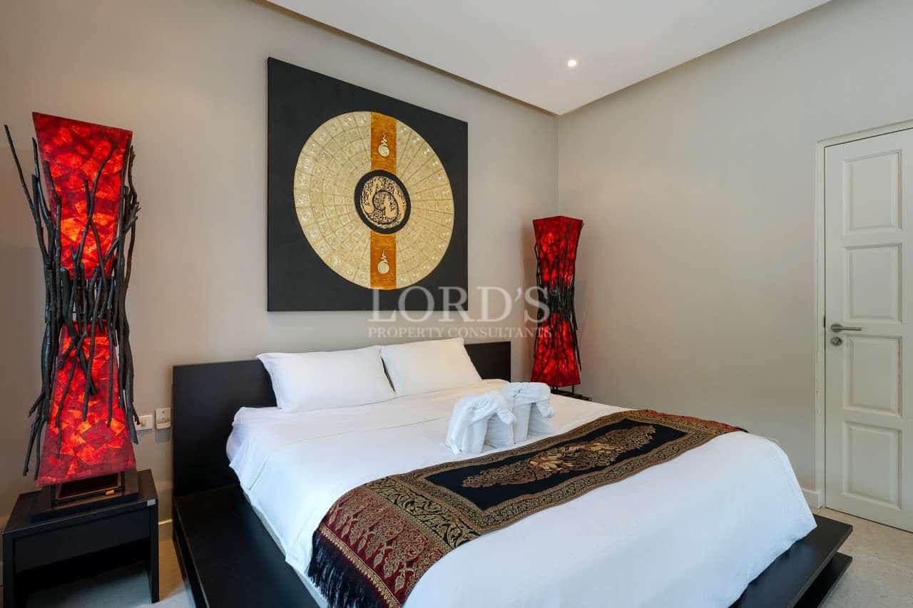 Luxury bedroom with king-size bed, Asian wall art, and red ambient floor lamps.