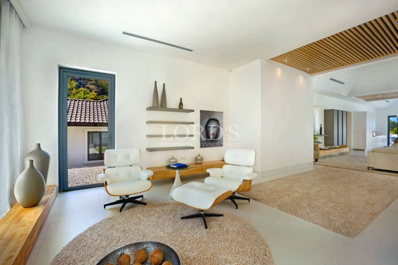 Modern minimalist lounge area with white lounge chairs, wooden accents, neutral rugs, and open-plan luxury interior.