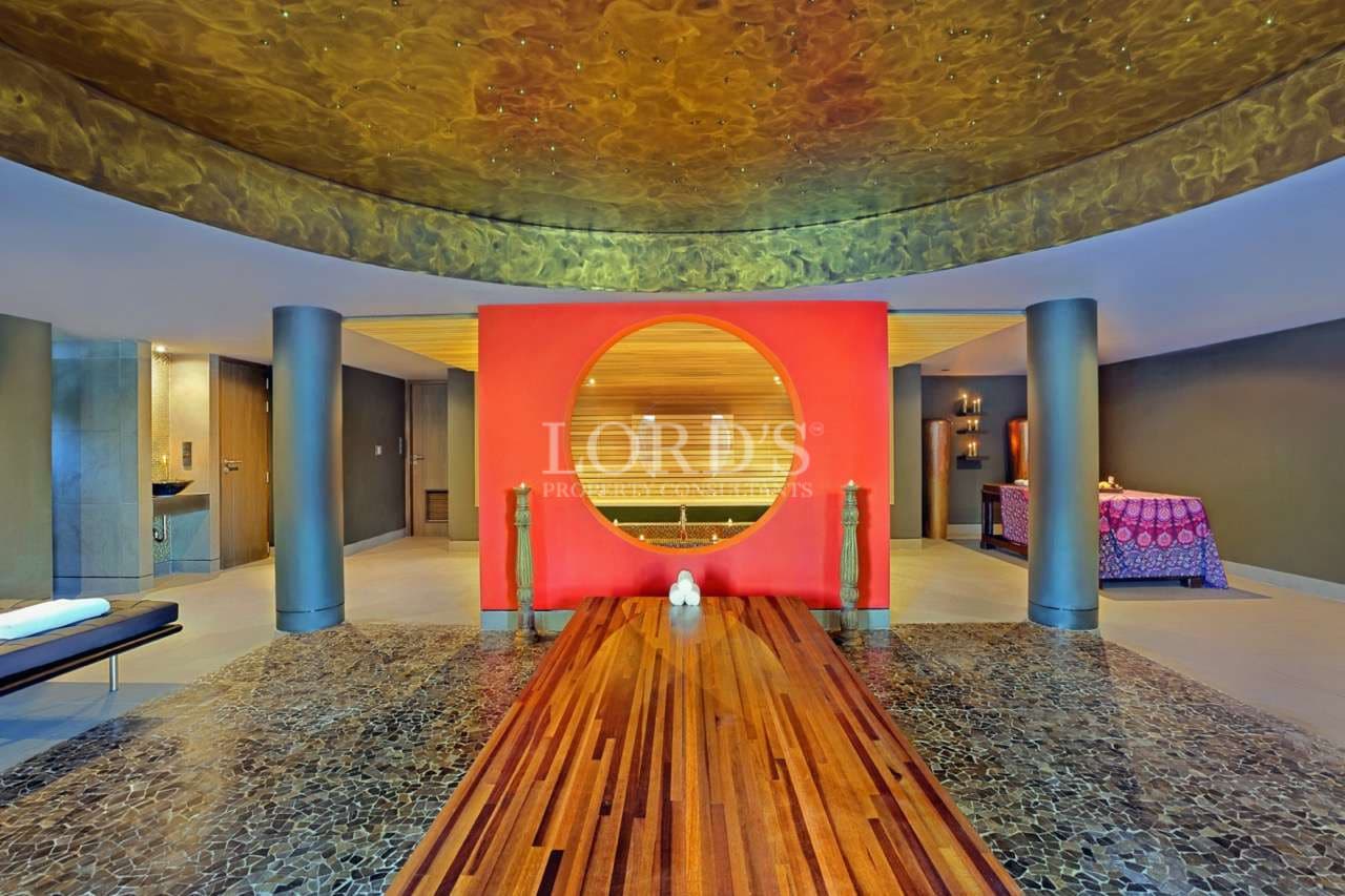 Luxury spa interior with circular red feature wall, wooden walkway, and ambient ceiling lighting.