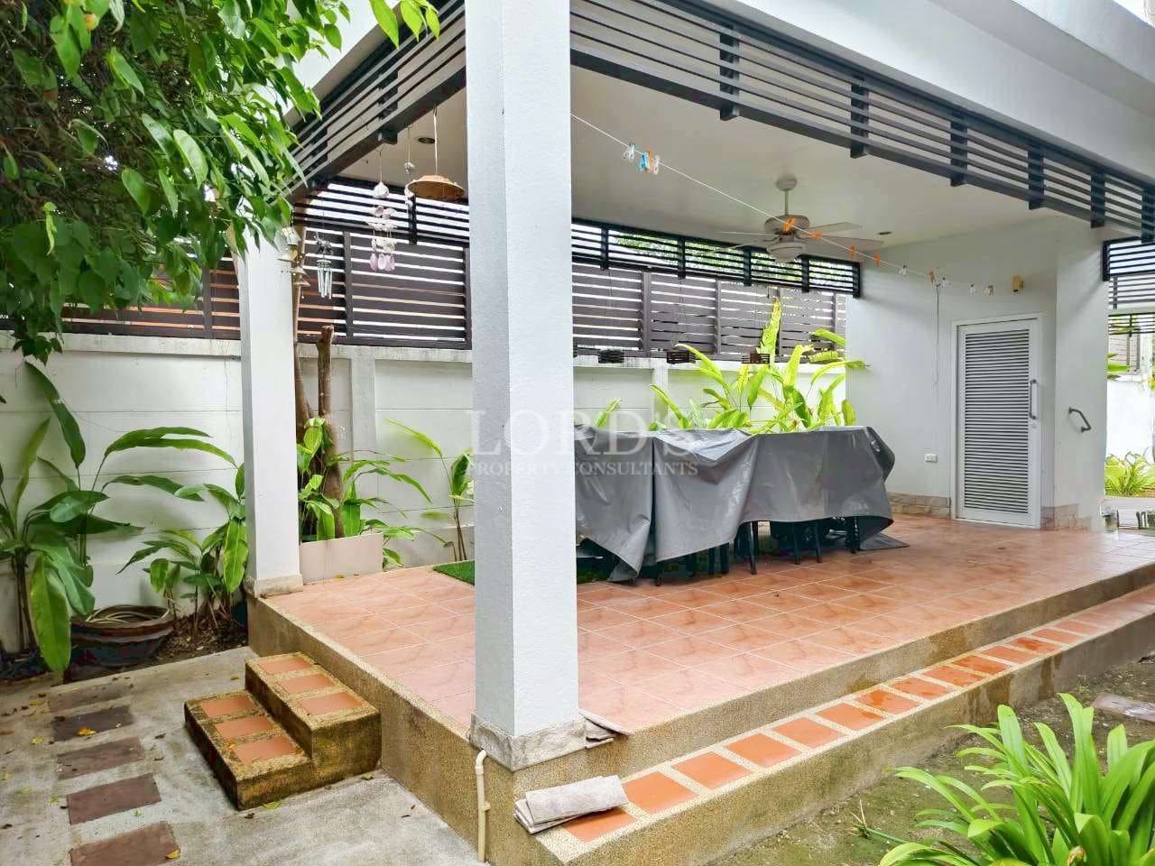 Covered patio with greenery and furniture