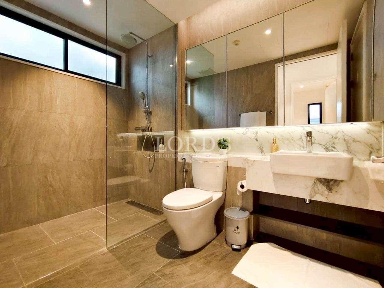 Modern bathroom with glass walk-in shower, marble vanity, large mirror, and neutral tile finishes