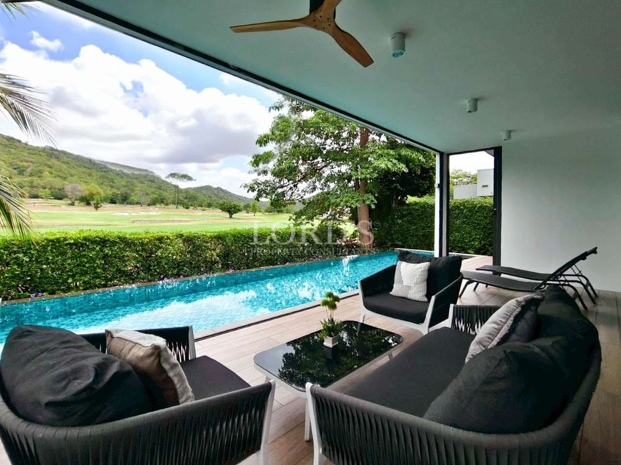 Covered poolside lounge with private swimming pool, outdoor seating, and scenic golf course views