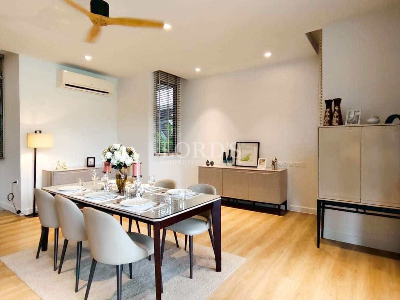 Modern dining room with wooden flooring, glass-top dining table, upholstered chairs, and ambient lighting