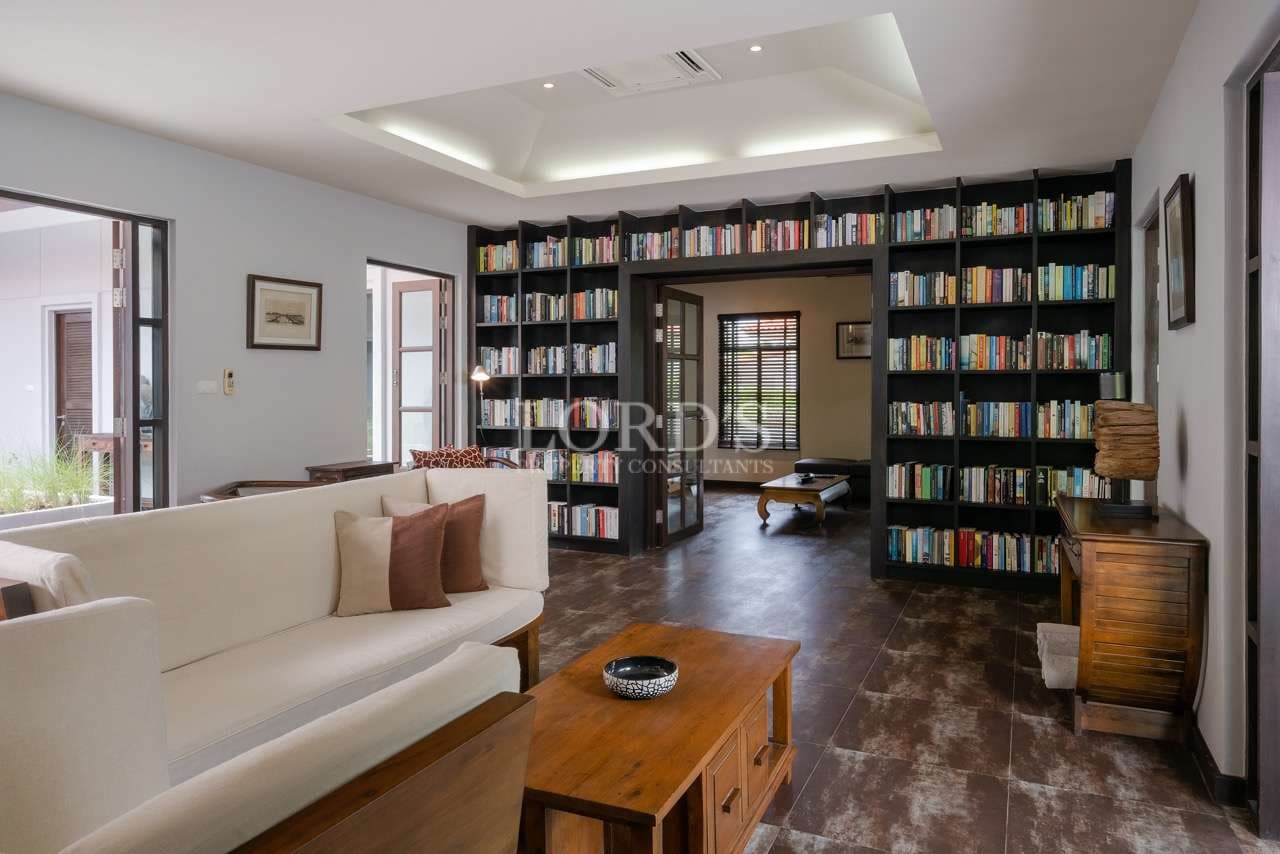Luxury home library with floor-to-ceiling bookshelves, modern seating, and open-plan living space.