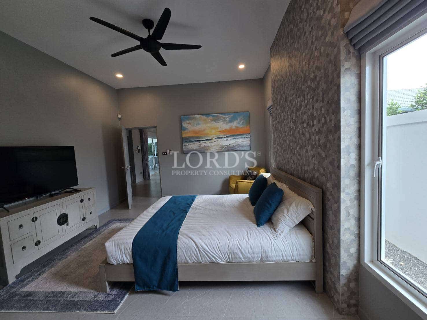 Modern bedroom with king-size bed, textured accent wall, ceiling fan, and large window.