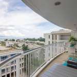 Curved balcony with outdoor seating overlooking ocean and modern residential buildings