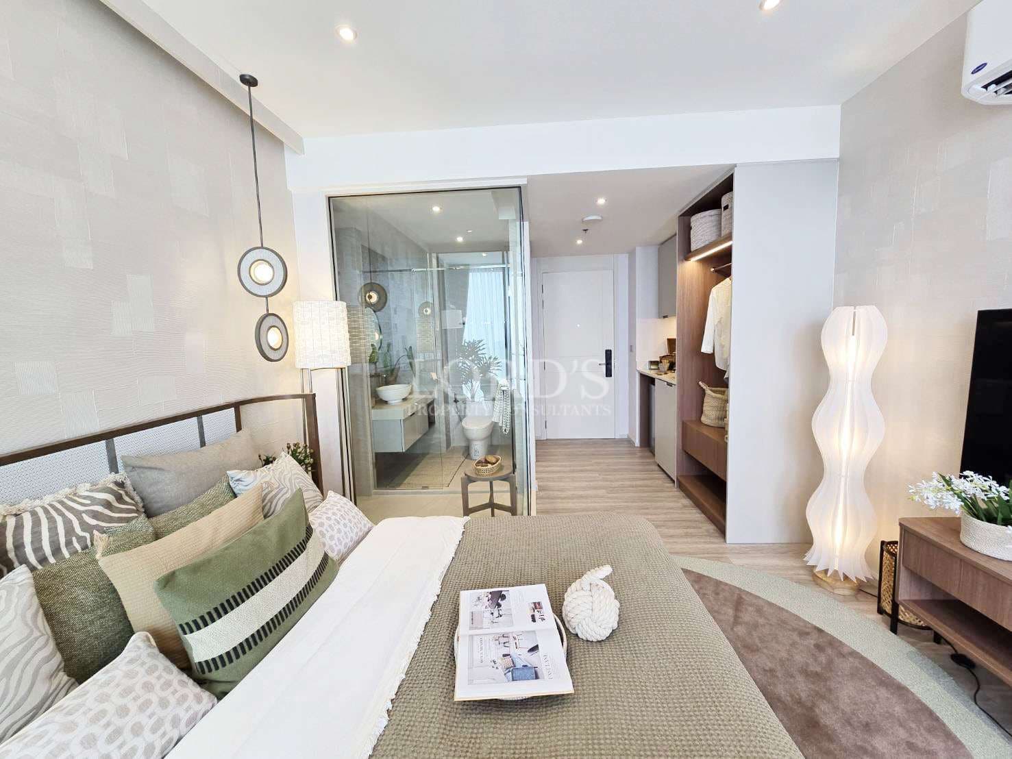 Modern bedroom interior with glass-enclosed bathroom, neutral-toned bedding, built-in wardrobe, soft ambient lighting, and minimalist decor.