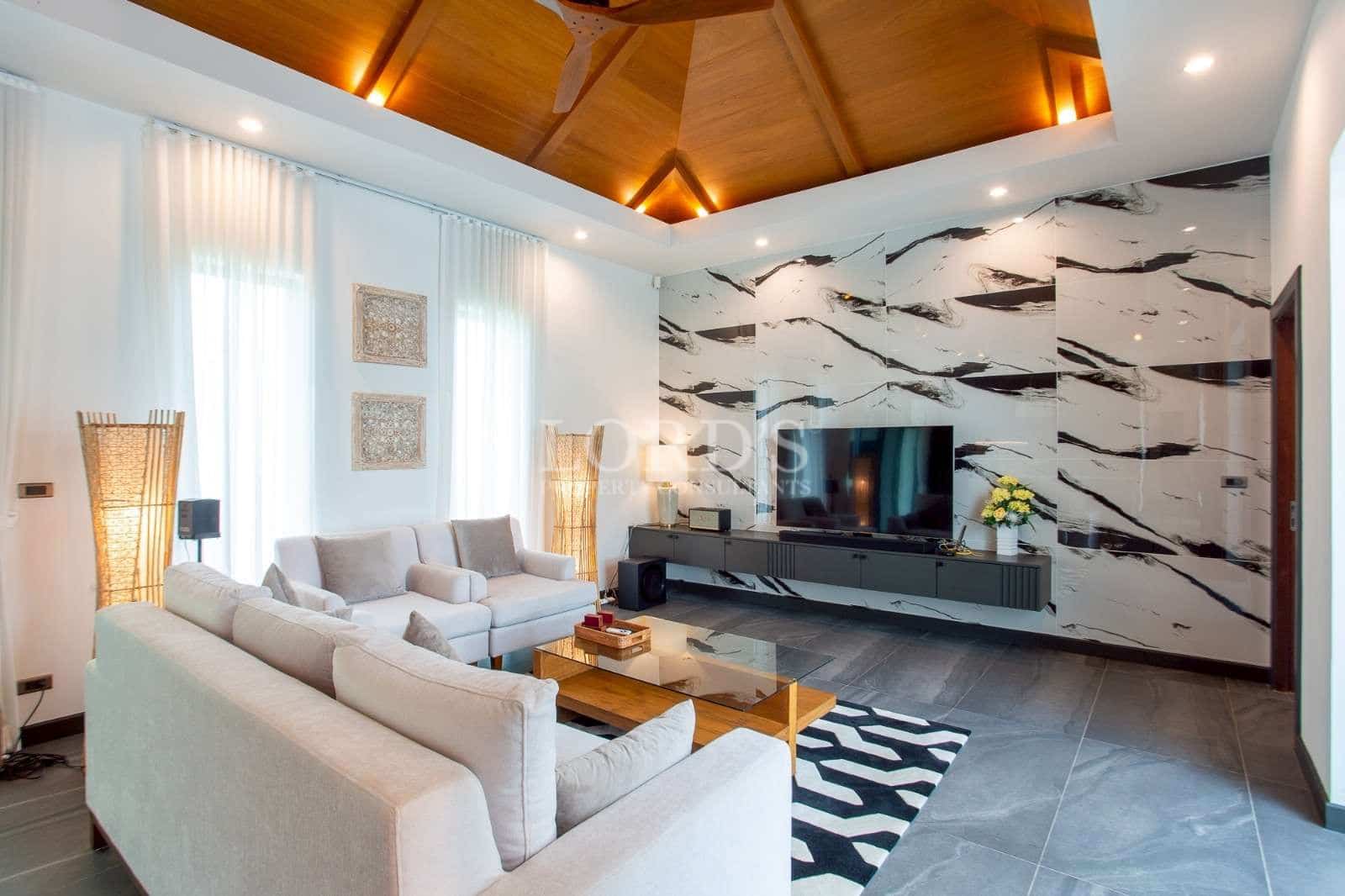 Modern living room with marble accent wall, wooden ceiling, and contemporary seating.