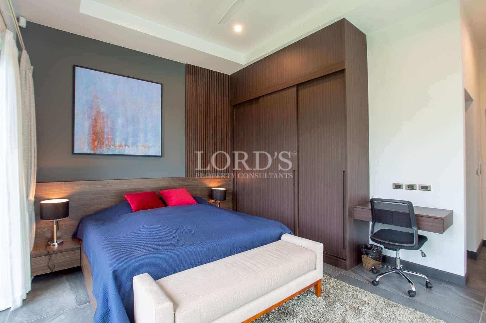 Modern bedroom with built-in wardrobe, work desk, and minimalist interior design.