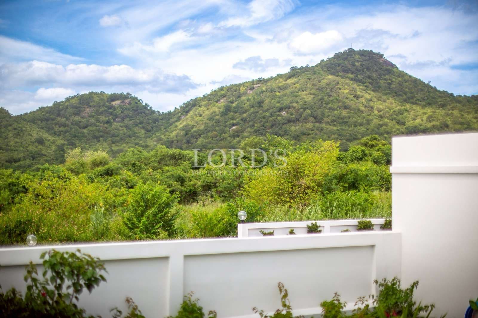 Scenic mountain view from a private villa with lush green surroundings and clear blue sky.
