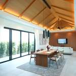 Luxury open-plan living and dining area with wooden ceiling, large glass doors, pendant lighting, and modern furniture.