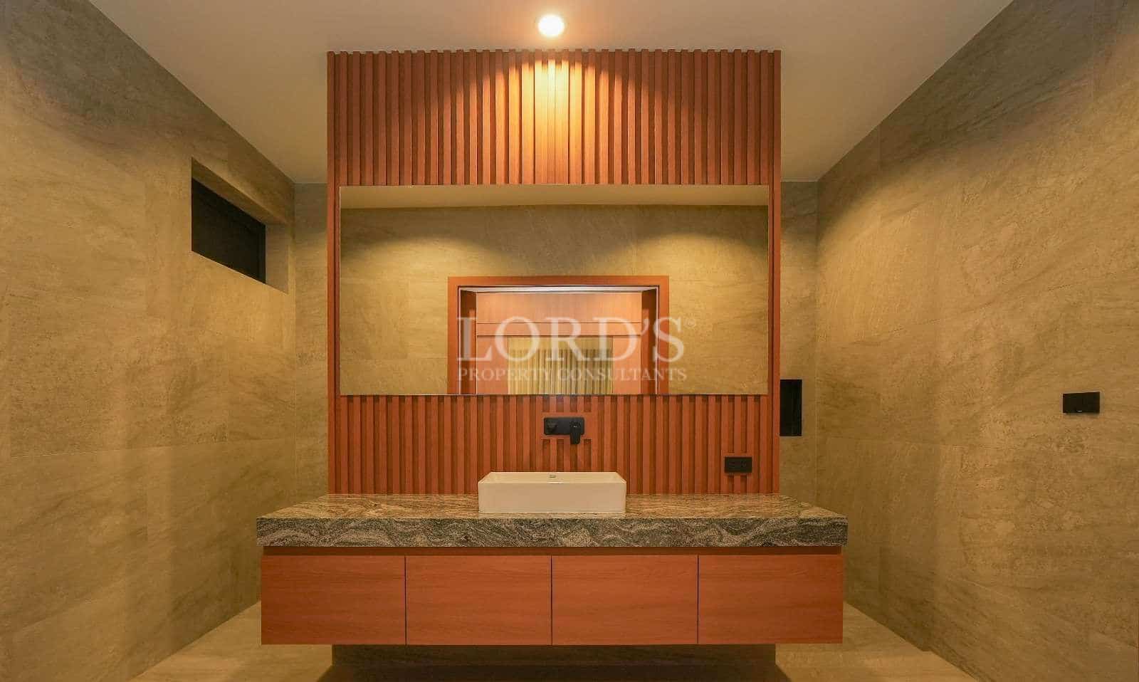 Luxury bathroom vanity with wooden paneling, stone countertop, rectangular sink, and warm ambient lighting.