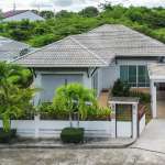 Single-story house with lush greenery.