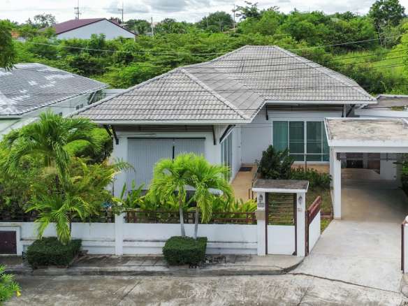 Single-story house with lush greenery.