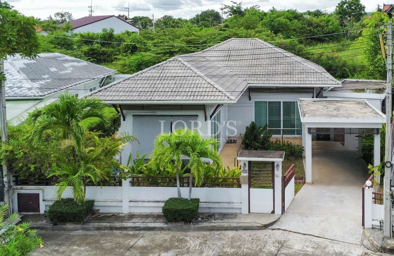 Single-story house with lush greenery.