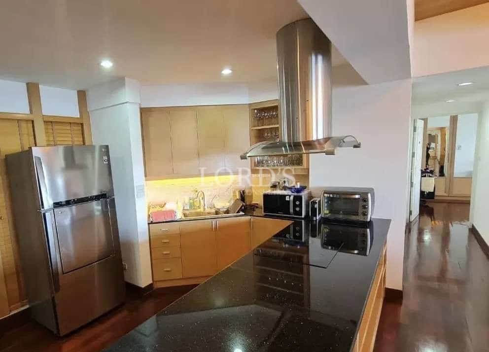 Modern kitchen with black granite island, stainless steel appliances, and built-in cabinetry.