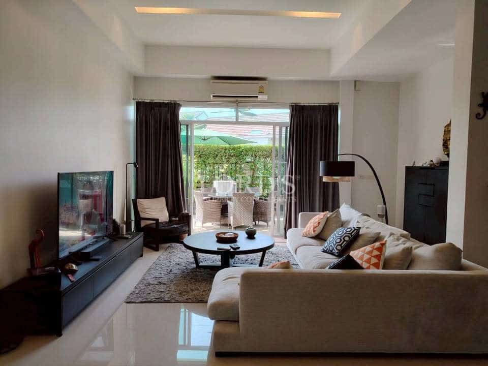 Modern living room with sofa seating, TV console, coffee table, floor lamp, and sliding glass doors to a patio.