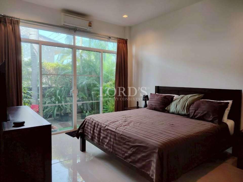 Modern bedroom with double bed, sliding glass doors, air conditioning, and garden view.
