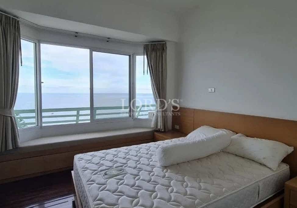 Minimalist bedroom with large window, ocean view, wooden bed frame, and natural light.