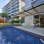 Modern apartment terrace with private swimming pool, pergola seating area, and landscaped garden.