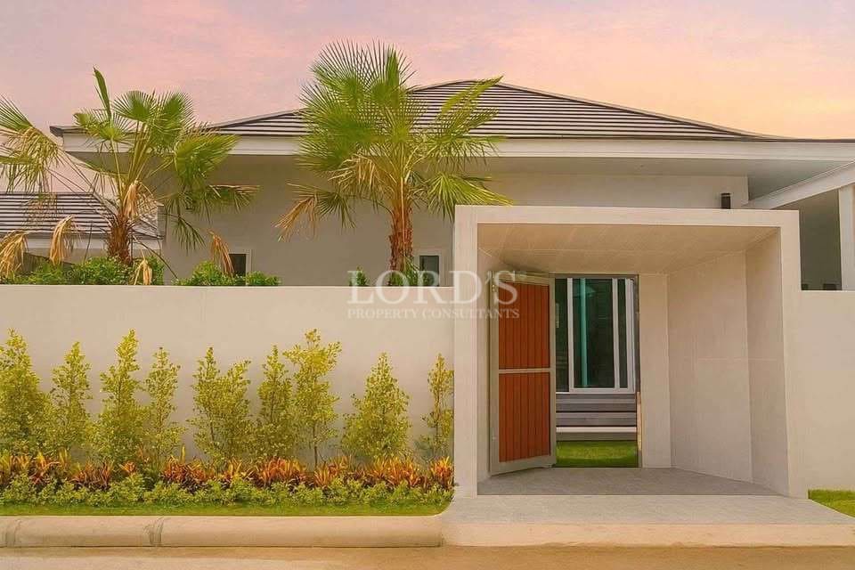 Modern luxury villa entrance with gated walkway, landscaped garden, and palm trees at sunset.
