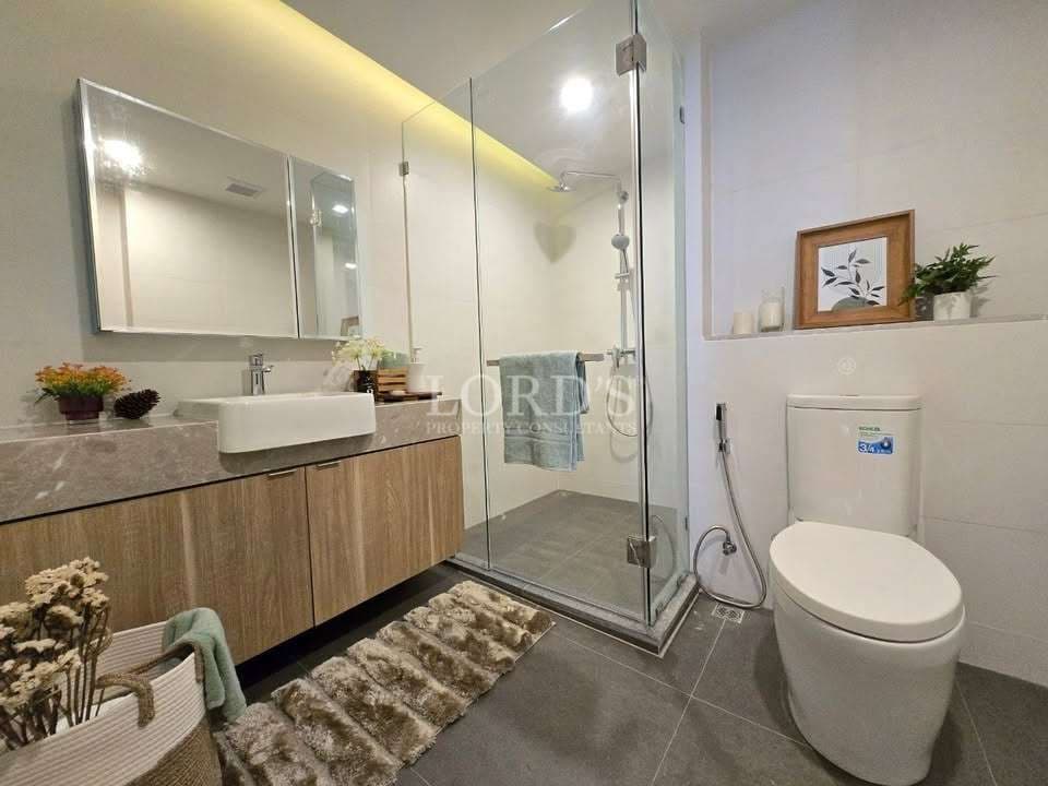 Modern bathroom with glass shower, wooden vanity, and contemporary toilet design.