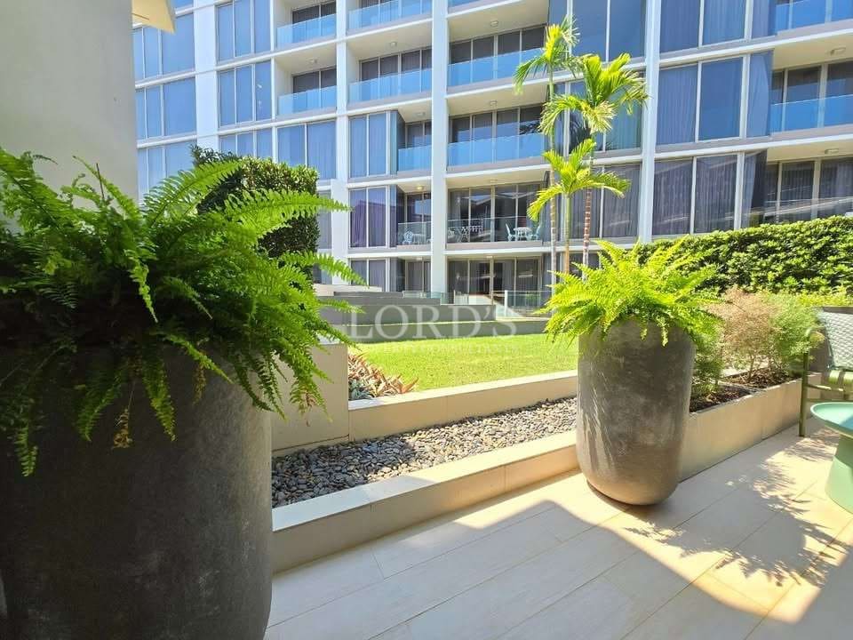 Landscaped garden terrace with potted plants and modern condominium building in the background.