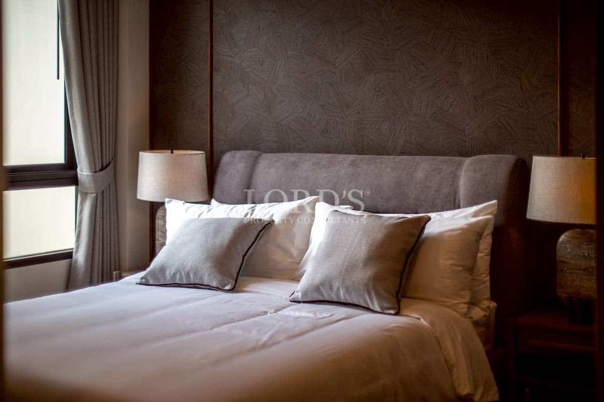 Elegant bedroom with upholstered headboard, soft neutral bedding, and warm bedside lighting.