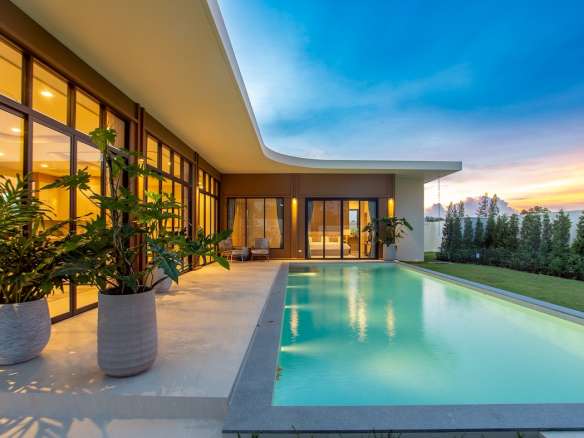 Modern luxury villa with private swimming pool, landscaped garden, and sunset lighting.