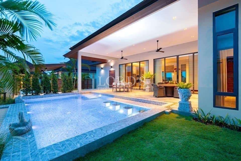Luxury modern villa with private swimming pool, landscaped garden, and covered outdoor living area at dusk.