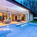 Luxury villa with private swimming pool, covered terrace, and outdoor dining area at night.