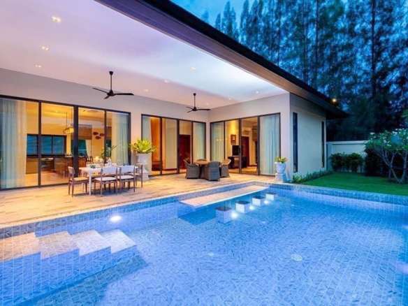 Luxury villa with private swimming pool, covered terrace, and outdoor dining area at night.