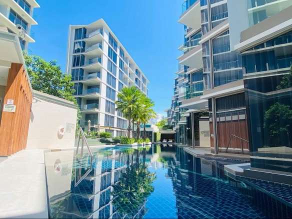 Modern luxury condominium with swimming pool, glass balconies, palm trees, and contemporary architecture.