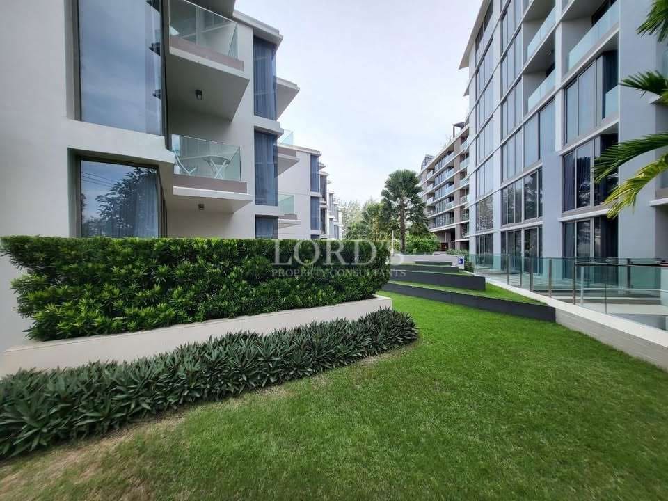 Landscaped garden walkway between modern apartment buildings with glass balconies.