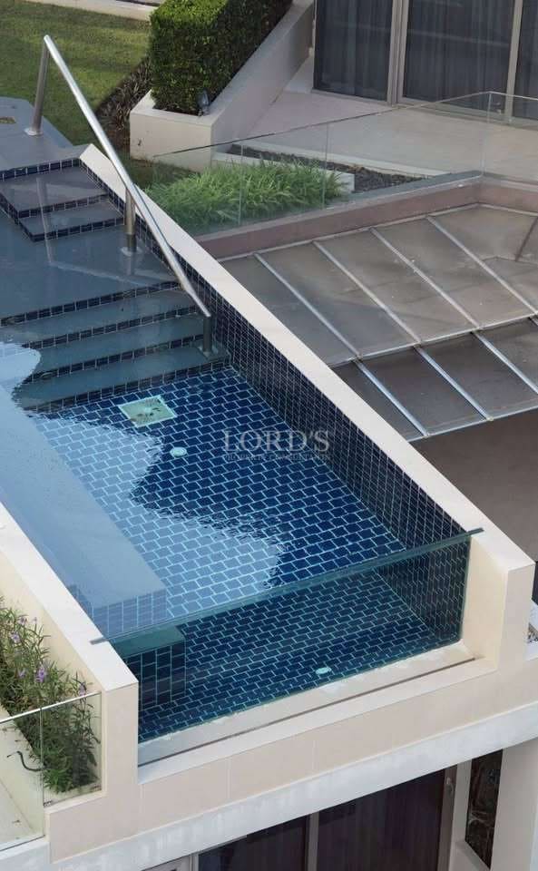 Glass-edge swimming pool with modern tile finish and pool steps.