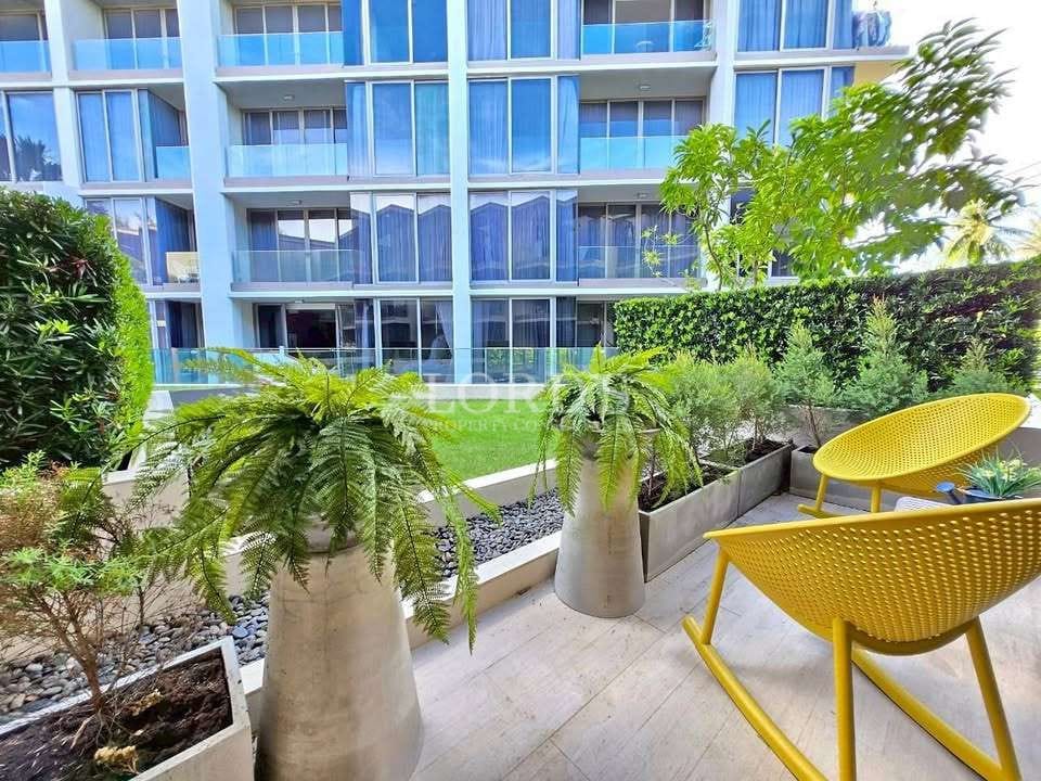 Modern apartment balcony with yellow chairs, potted plants, and garden view.