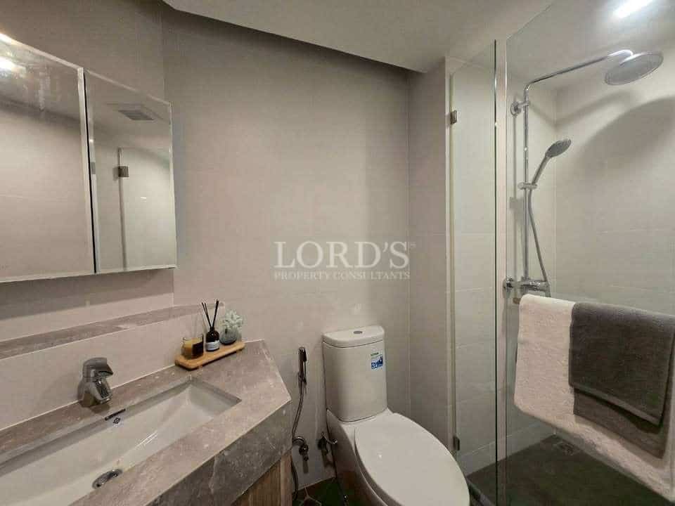 Modern bathroom with glass shower enclosure, toilet, and vanity sink.