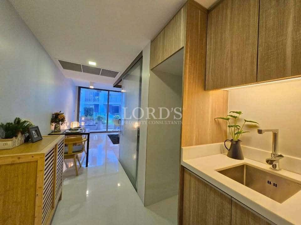 Modern apartment kitchenette with wood cabinets, sink, and open-plan dining area.