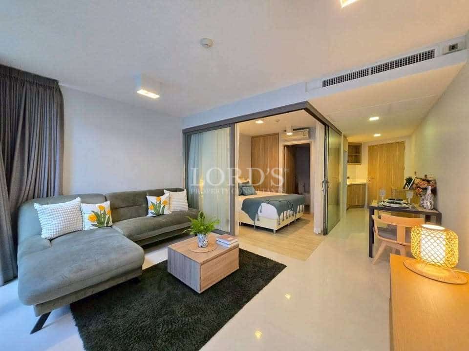 Modern open-plan living room with sofa, sliding glass bedroom partition, and dining area.