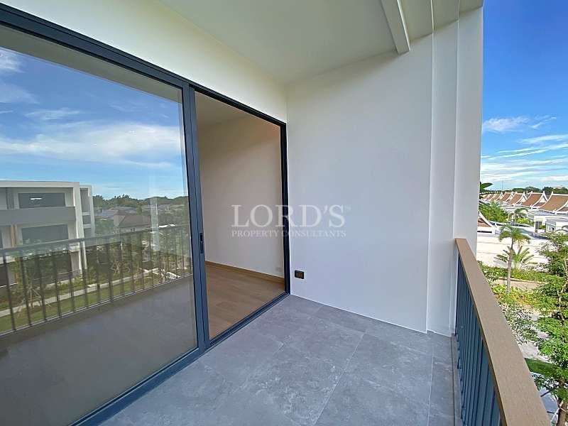 Private apartment balcony with sliding glass doors, tiled flooring, and views of landscaped residential surroundings.