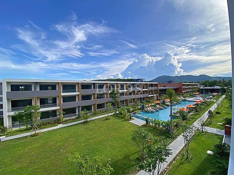 Resort-style residential complex with swimming pool, landscaped gardens, modern low-rise buildings, and mountain views.