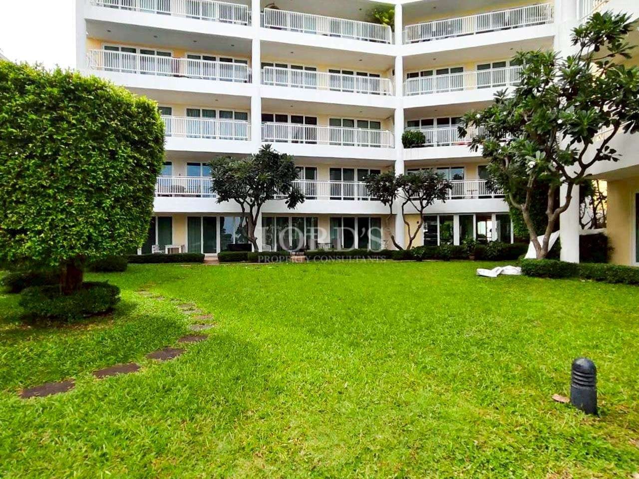 Landscaped garden courtyard with green lawn surrounded by modern condominium balconies.