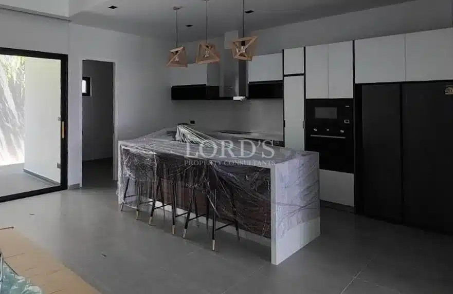 Modern kitchen with marble island, bar stools, built-in appliances, and pendant lighting.