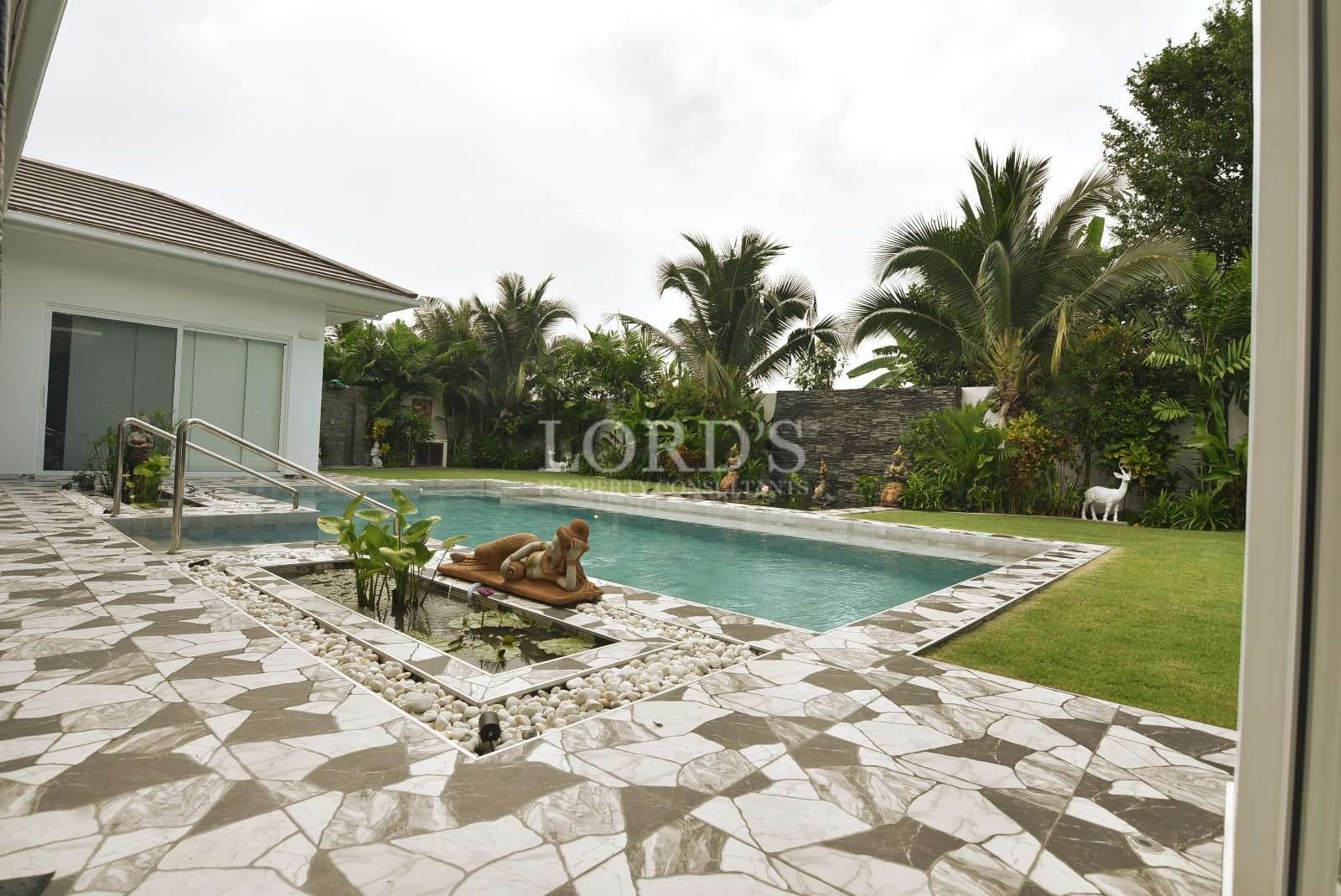 Luxury private swimming pool with landscaped garden, palm trees, and modern villa patio.